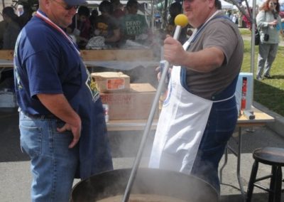 people talking while cooking cracklins around a pot